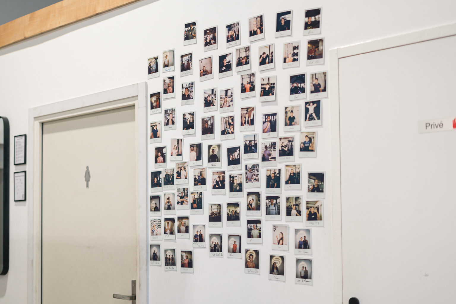 Le mur des membres : des polaroïds d’adhérents affichés près des vestiaires
